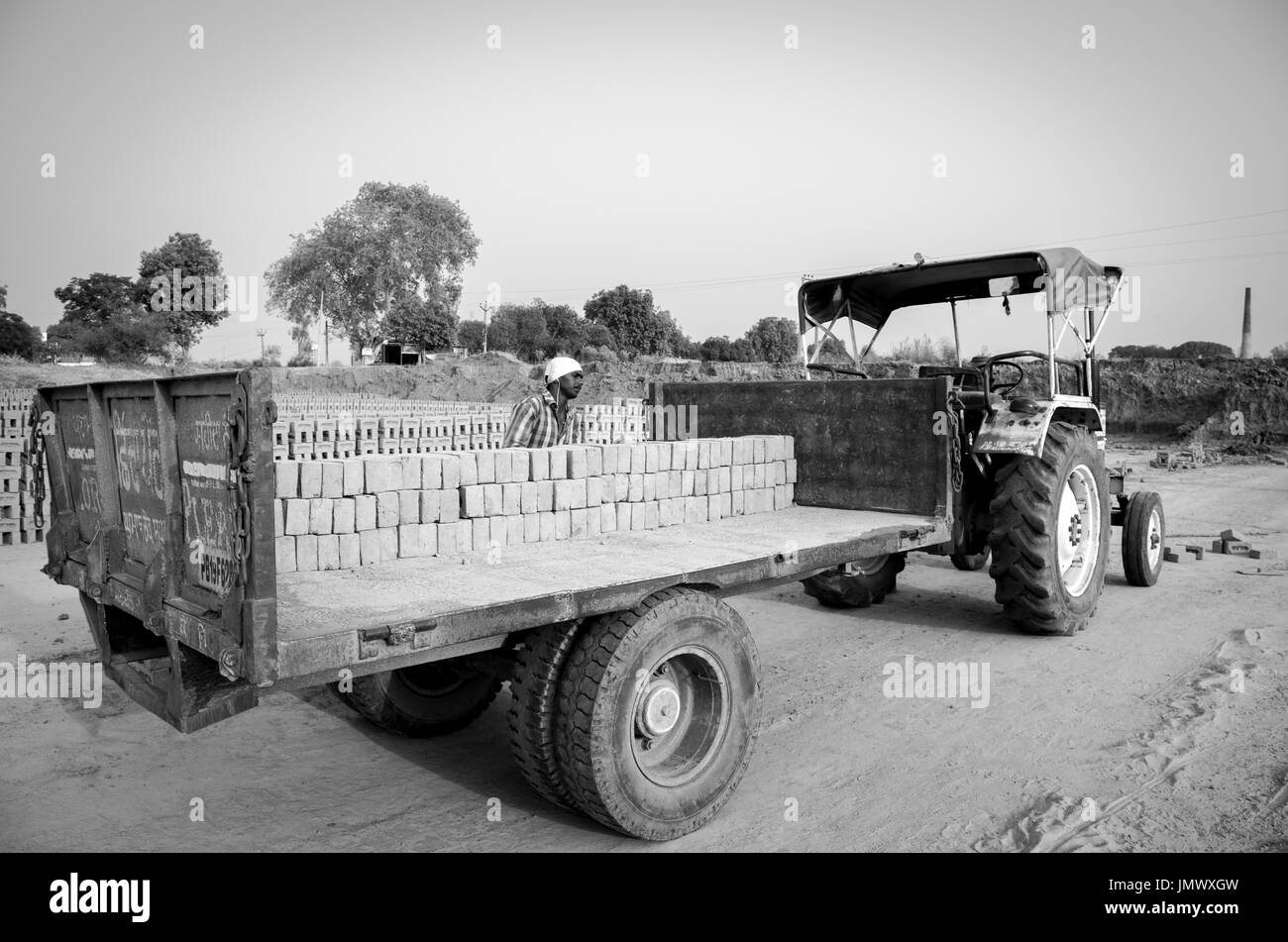 Amritsar, Punjab, Indien - 21. April 2017: Schwarzweiß-Bild von Backsteinen auf einem Lkw, an der ein Arbeitnehmer bereit für einen Großmarkt Versand geladen werden Stockfoto