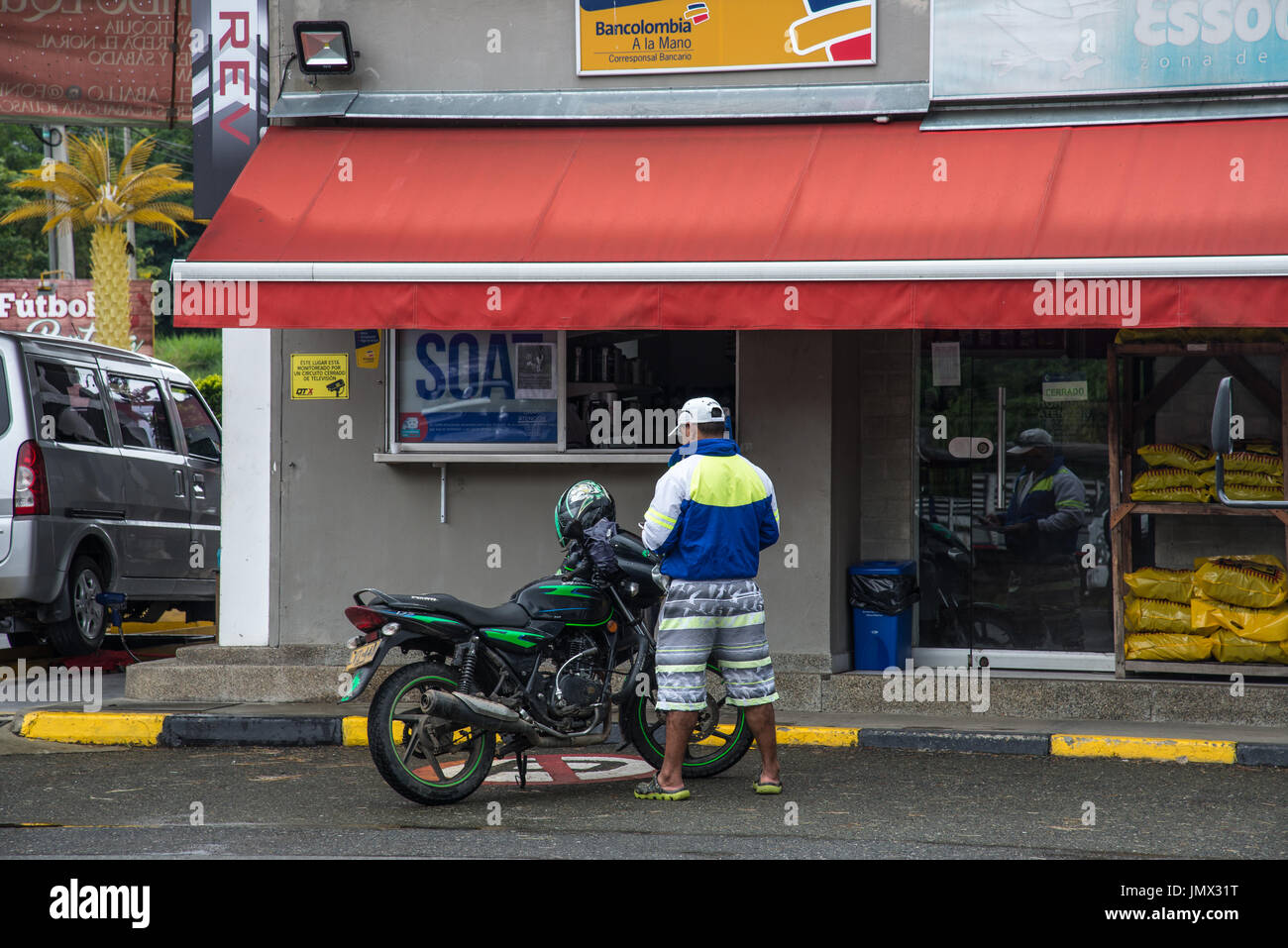 Ein Mann mit seinem Motorrad vor einem Geschäft steht. Medellin, Kolumbien, Südamerika. Stockfoto