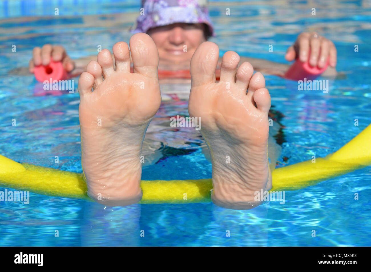 Cool bleiben! Frau schwimmt auf zwei Poolnudeln in einem Schwimmbad. Einfach nur chillen. Stockfoto