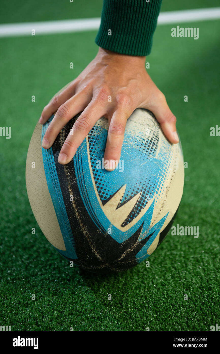 Nahaufnahme von Hand mit Rugby-Ball auf Feld Stockfoto
