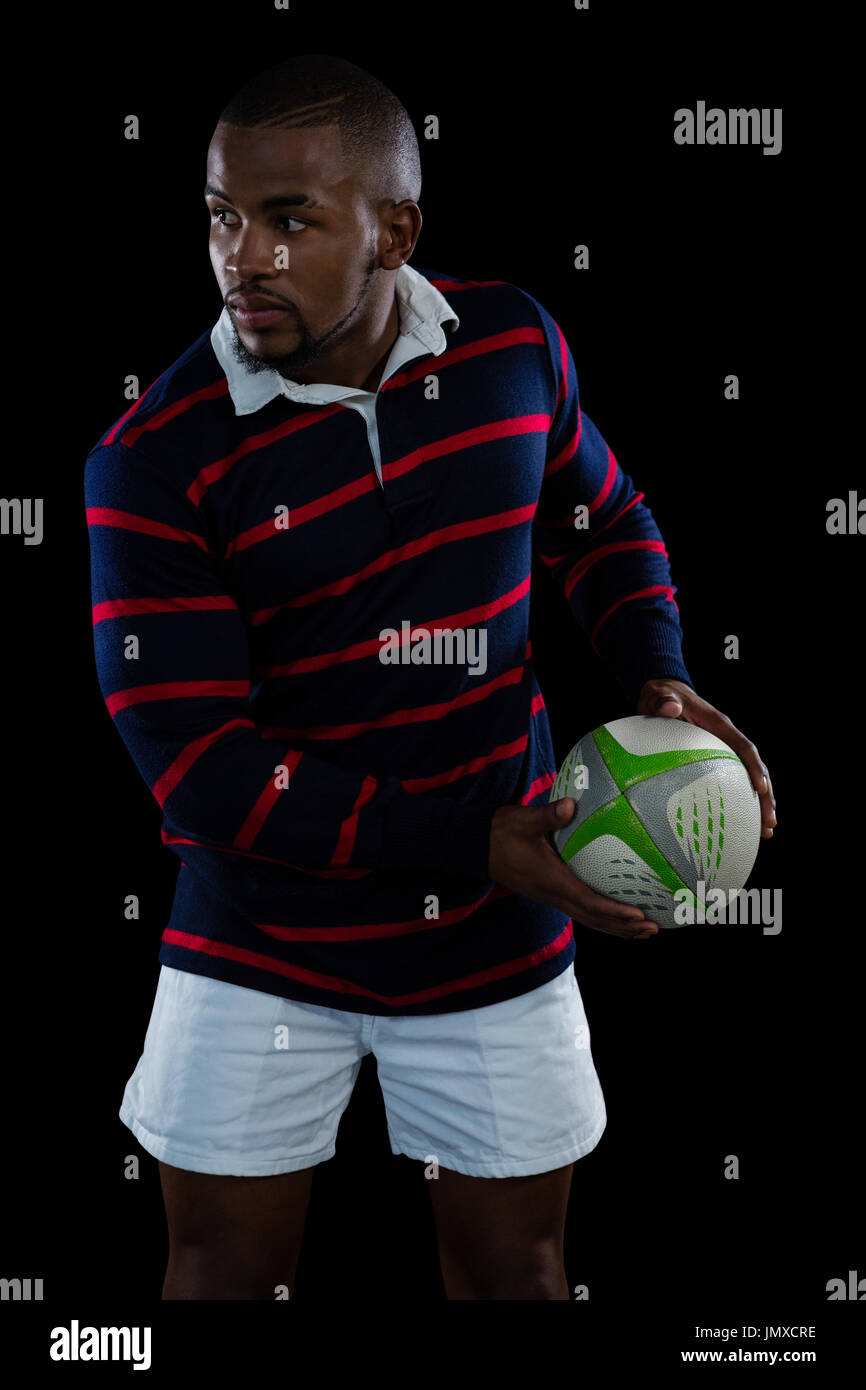 Athlet mit Rugby-Ball stehend auf schwarzem Hintergrund Stockfoto