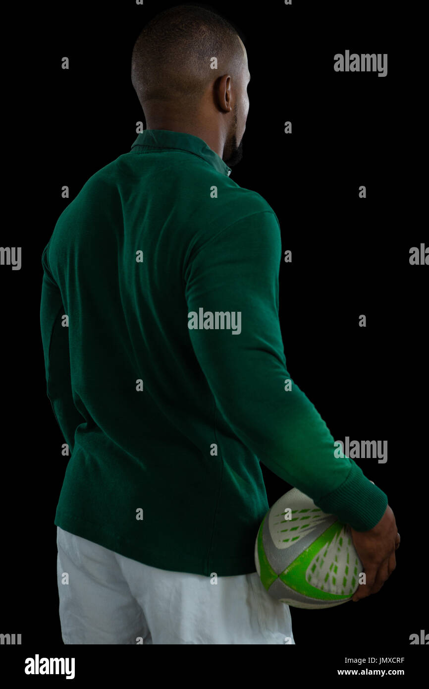 Rückansicht des männlichen Spieler mit Rugby-Ball stehend auf schwarzem Hintergrund Stockfoto