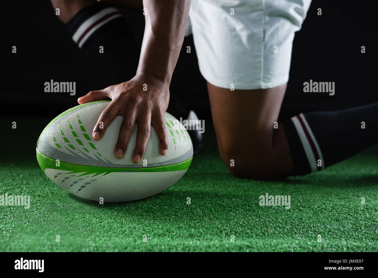 Seitenansicht der Sportler kniet auf Feld mit gedrückter Rugby-ball Stockfoto