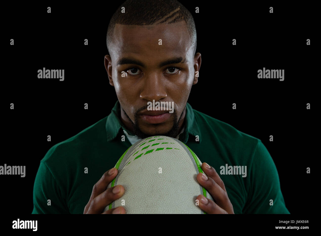 Porträt von zuversichtlich männlicher Athlet mit Rugby-Ball vor schwarzem Hintergrund hautnah Stockfoto