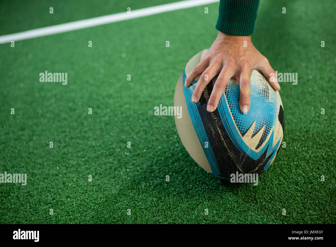 Hand der Frau mit Rugby-Ball auf Feld abgeschnitten Stockfoto