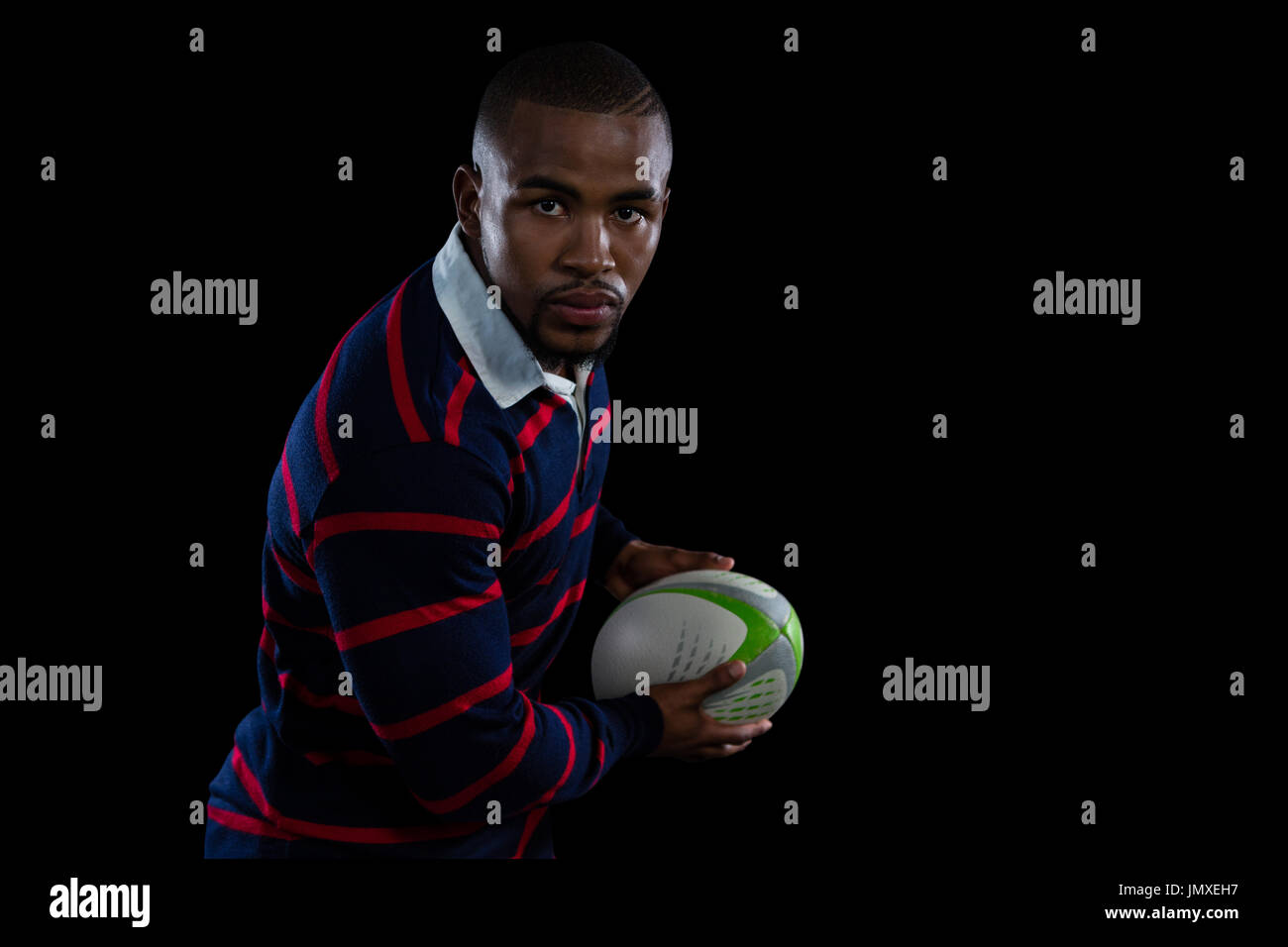 Porträt von männlichen Athleten mit Rugby-Ball stehend auf schwarzem Hintergrund Stockfoto