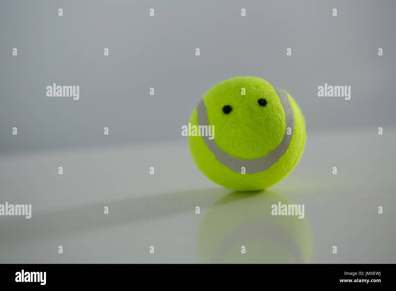 Nahaufnahme eines Tennisballs mit anthropomorphen Gesicht vor weißem Hintergrund Stockfoto