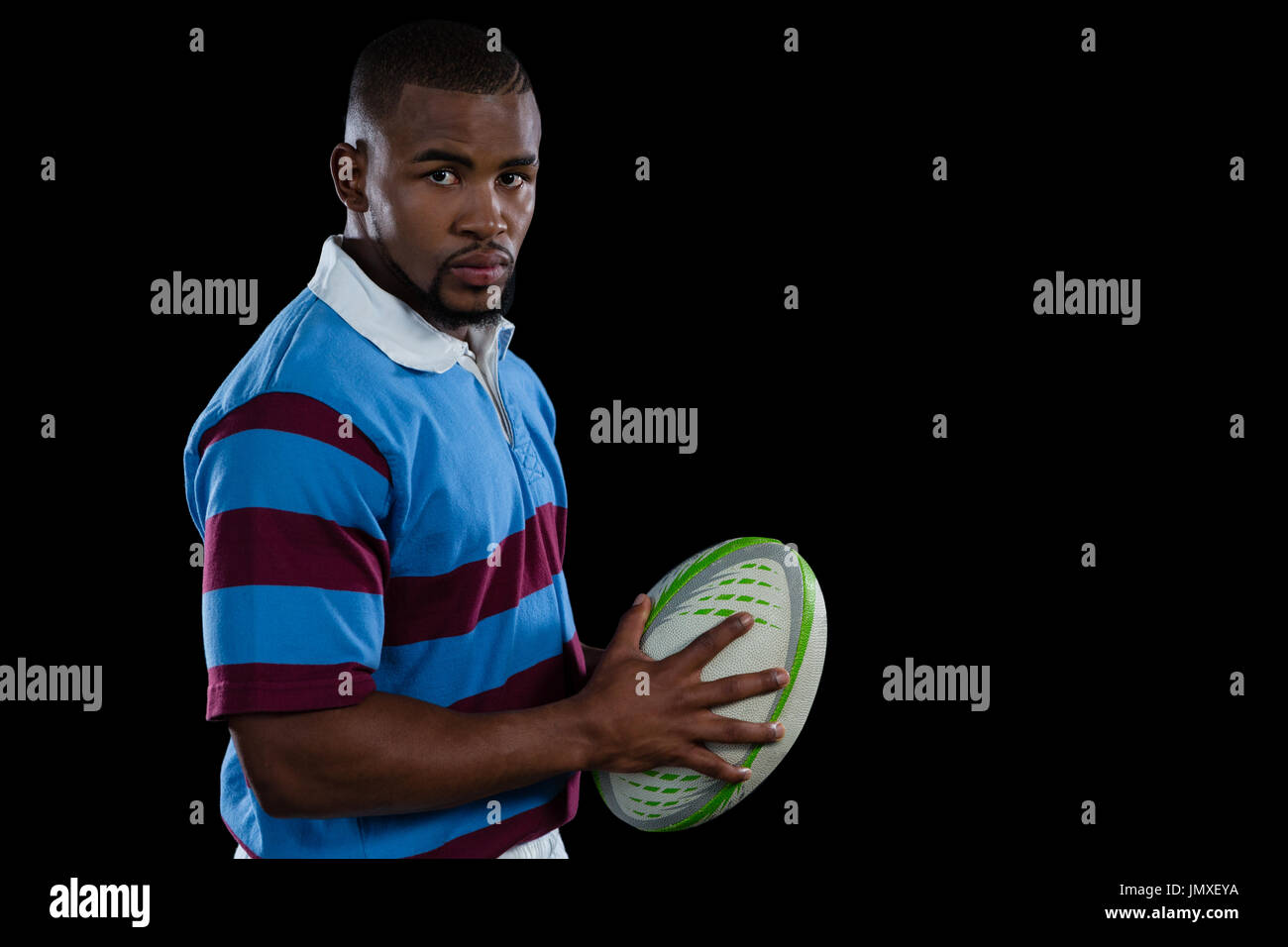 Porträt von zuversichtlich männliche Spieler mit Rugby-Ball stehend auf schwarzem Hintergrund Stockfoto
