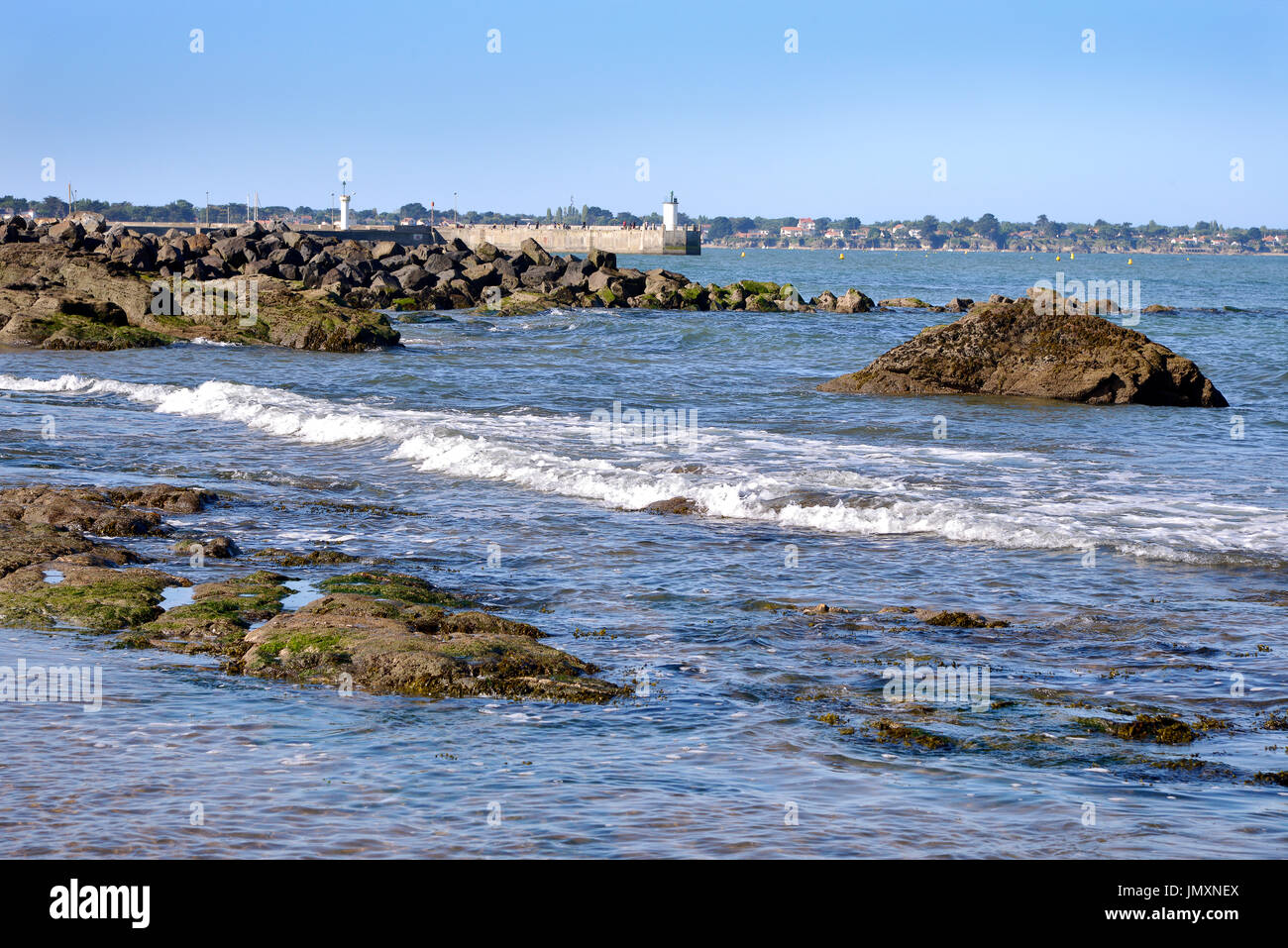 Felsige Küste mit den Leuchttürmen der Hafen im Hintergrund bei Saint-Michel-Chef-Chef im Departement Loire-Atlantique in Westfrankreich. Stockfoto