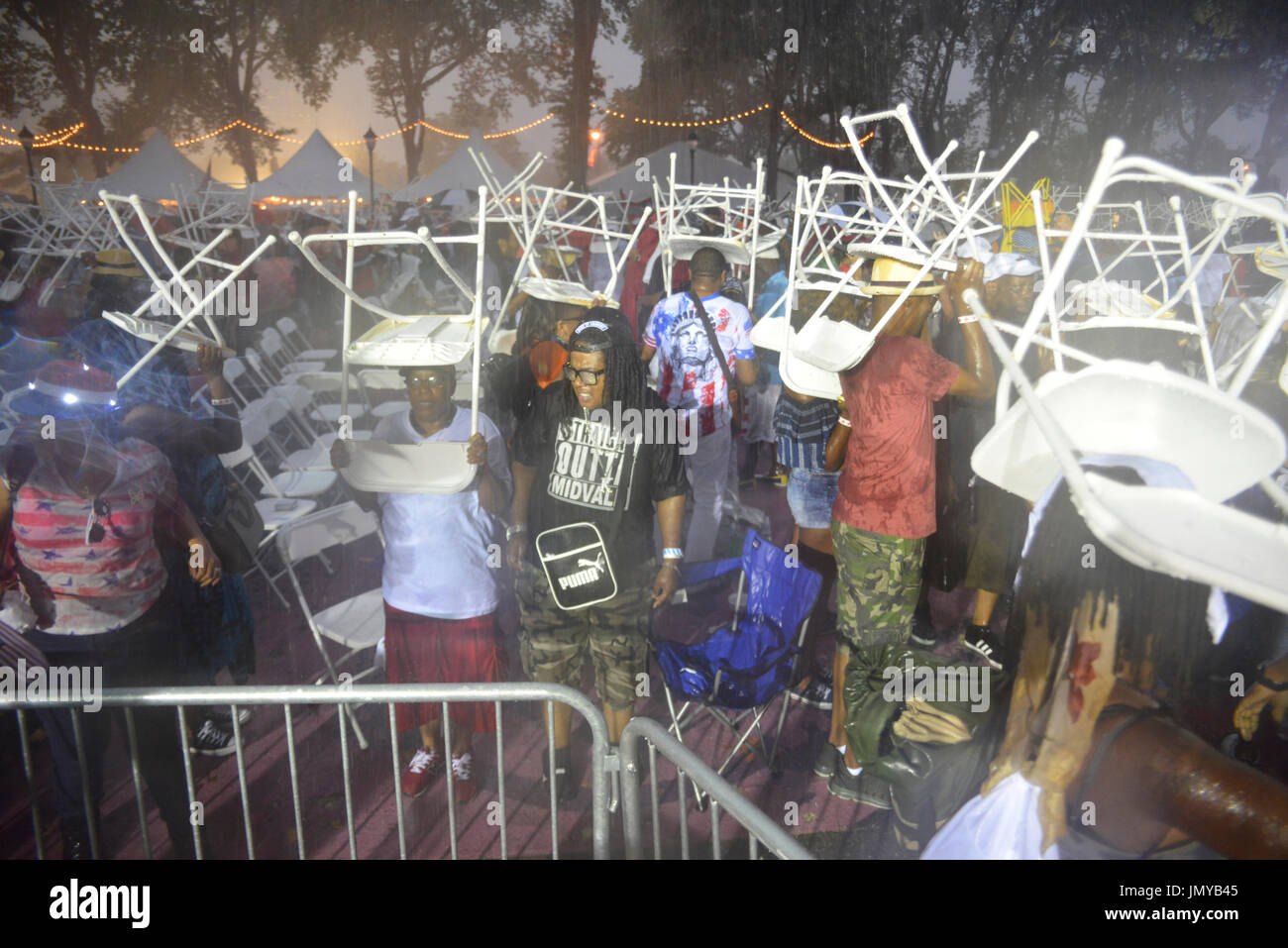 Menschen Gerangel um Unterschlupf zu finden, da die Menge der WaWa Welcome America Konzertbesuch von sintflutartigen Regen überrascht wird Stockfoto