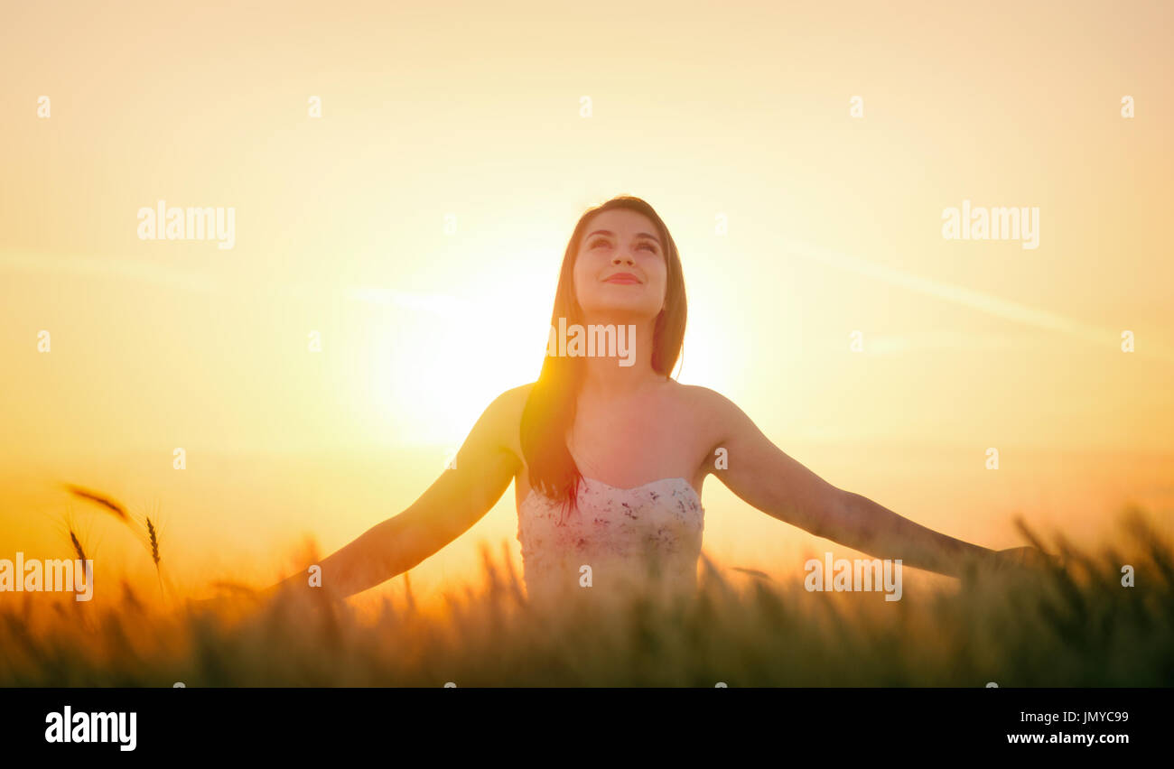 Schöne Frau im Sommer im Weizenfeld bei Sonnenuntergang Stockfoto