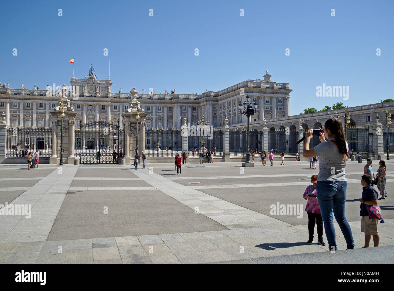 Nehmen Gruppe von Touristen Fotos von Palacio Real (Königlicher Palast) in Madrid, Spanien, in einer sehr sonnigen Tag mit ungetrübter blauer Himmel. Stockfoto