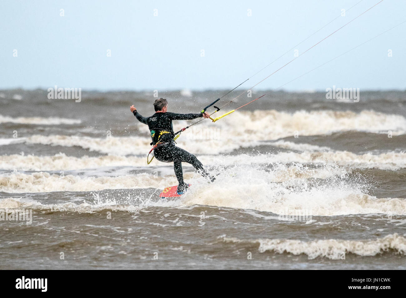 Southport, Merseyside, 29. Juli 2017. Großbritannien Wetter. Kite Boarder Kopf in die irische See, die Wellen auf die Flut an Southport Strand in Merseyside fahren. Stürmischen 25 km/h Wind macht nahezu perfekte Bedingungen um die Segel an dieser bekannten Kite boarding Hotspot zu füllen. Bildnachweis: Cernan Elias/Alamy Live-Nachrichten Stockfoto