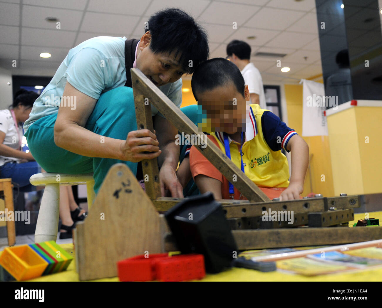 Peking, China. 29. Juli 2017. Ein Erwachsener hilft ein autistisches Kind Montage ein Möbelstück in ein interaktives Spiel in einer Kampagne, Liebe der autistischen Kinder in Peking 29. Juli 2017 zu zeigen. Bildnachweis: Ren Pengfei/Xinhua/Alamy Live-Nachrichten Stockfoto