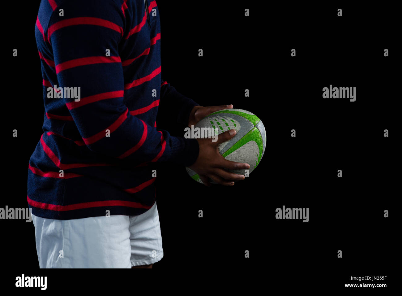 Mittleren Bereich der männlichen Spieler mit Rugby-Ball stehend gegen schwarze backgrouns Stockfoto