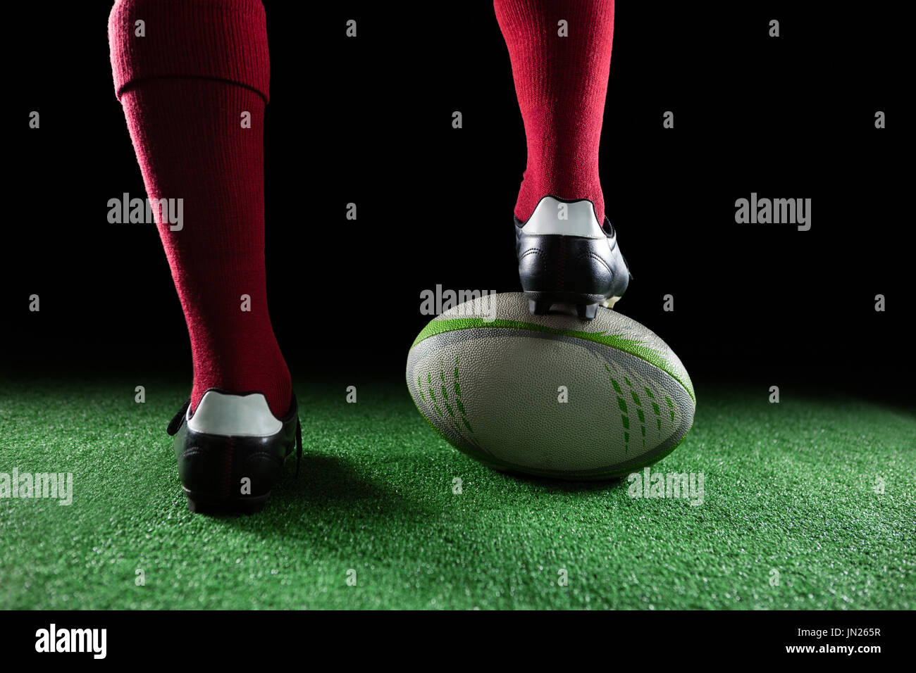 Nahaufnahme von Sportler verstärkt auf Rugby-Ball auf schwarzem Hintergrund Stockfoto