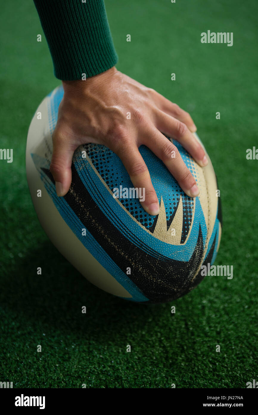 Bild von Hand mit Rugby-Ball auf Spielfeld beschnitten Stockfoto