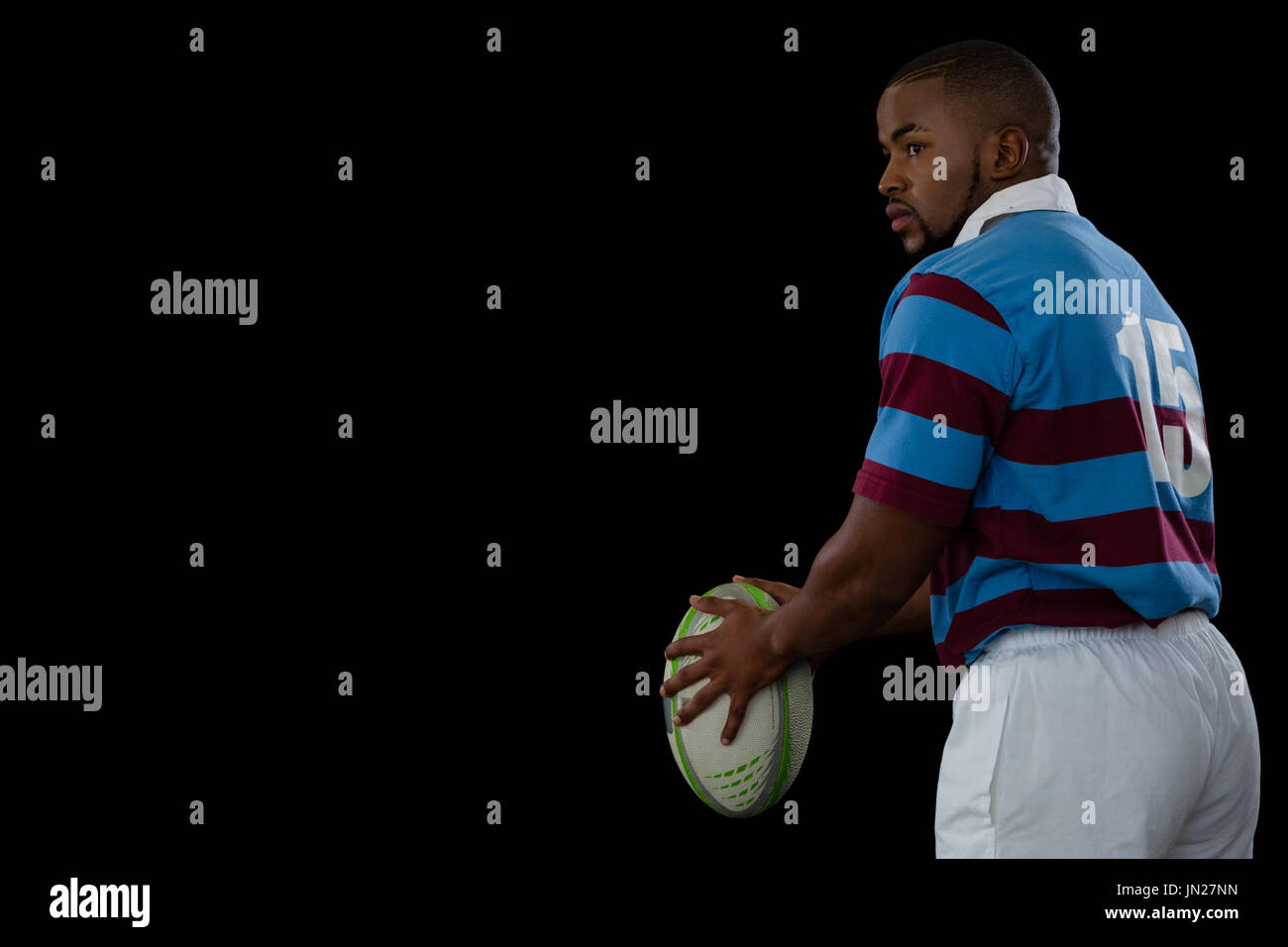 Seitenansicht der Sportler halten Rugby-Ball und wegsehen auf schwarzem Hintergrund Stockfoto