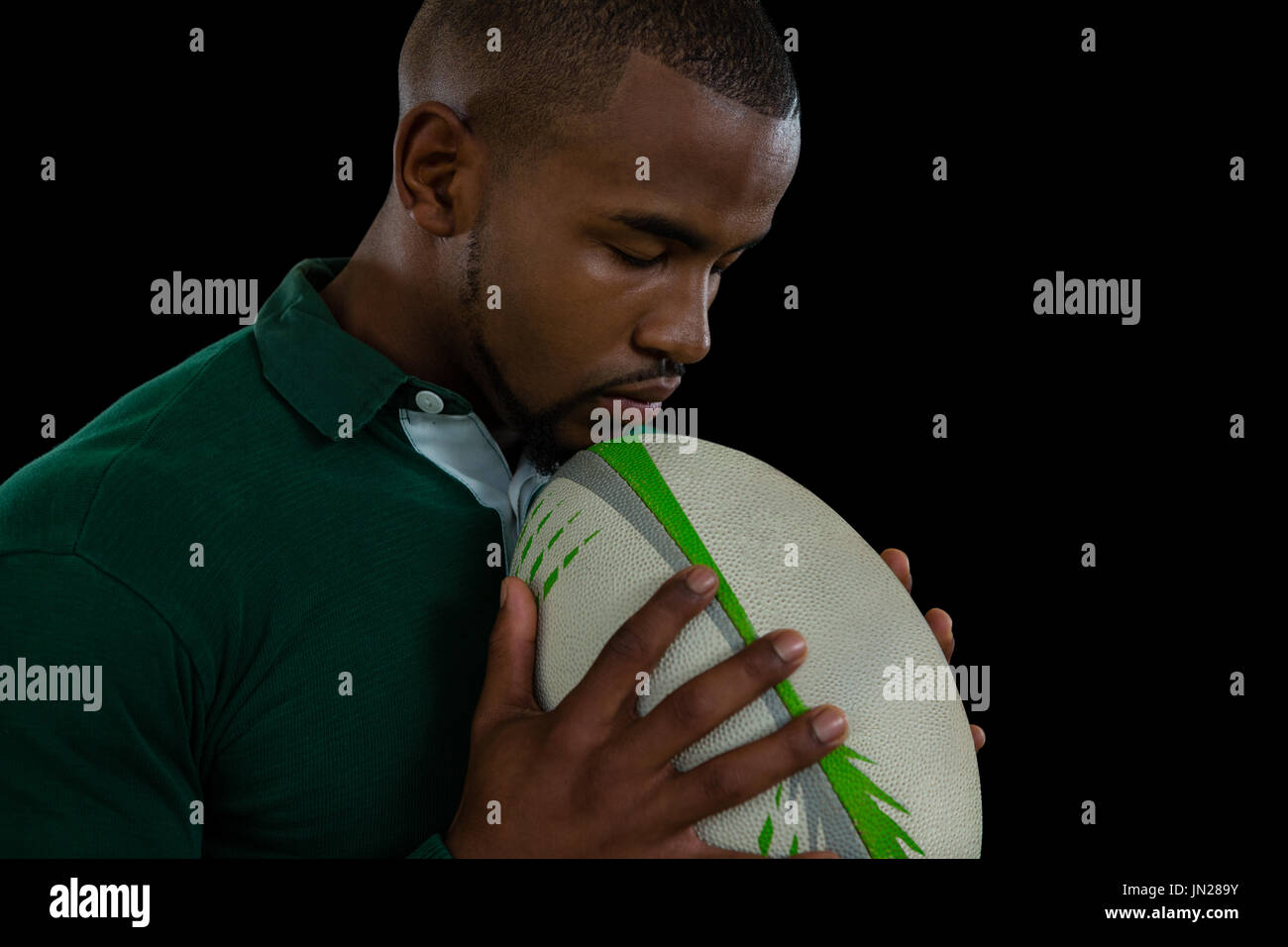 Seitenansicht des jungen Mannes mit Rugby-Ball auf schwarzem Hintergrund Stockfoto