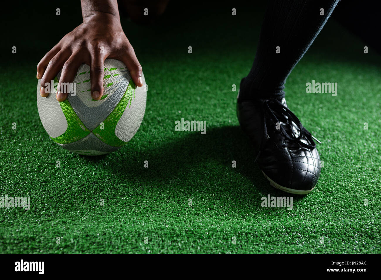 Nahaufnahme des Sportlers mit Rugby-Ball auf Feld Stockfoto