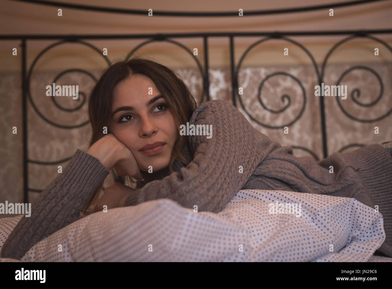 Nachdenkliche Frau wegsehen liegend im Bett zu Hause Stockfoto