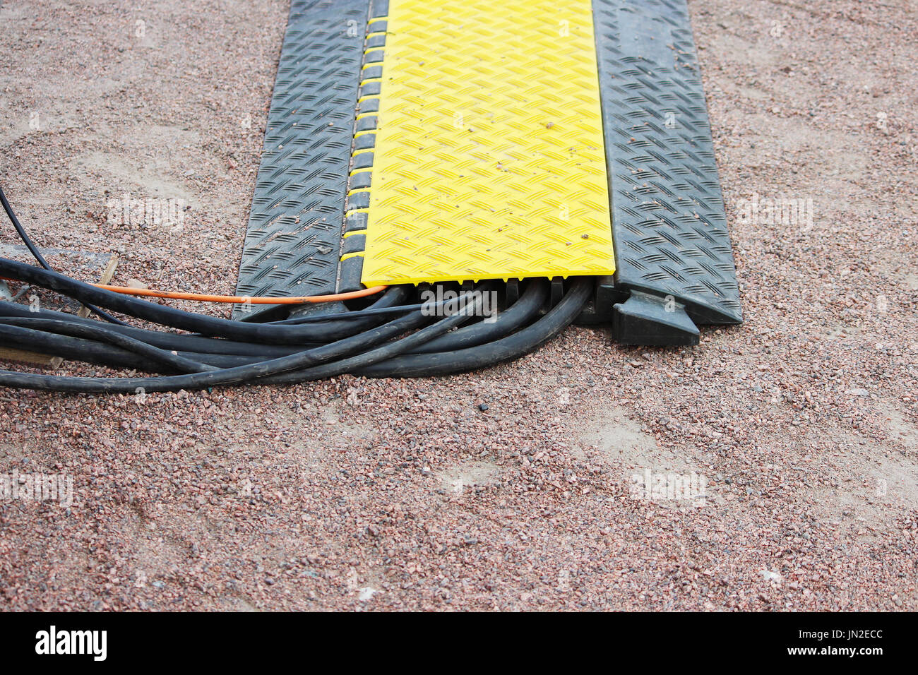 Viele Kabelkanäle mit elektrischen Video Belden Snake Kabel auf dem Boden liegt, während ein outdoor-Event Etage Schutz gelb schwarz Stockfoto