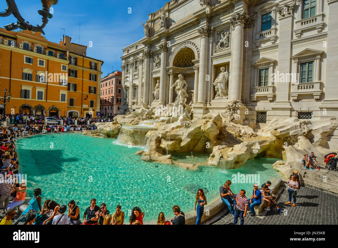 Das Meisterwerk Trevi Founatin an einem warmen Sommertag als Touristen sitzen und Spaß haben Stockfoto