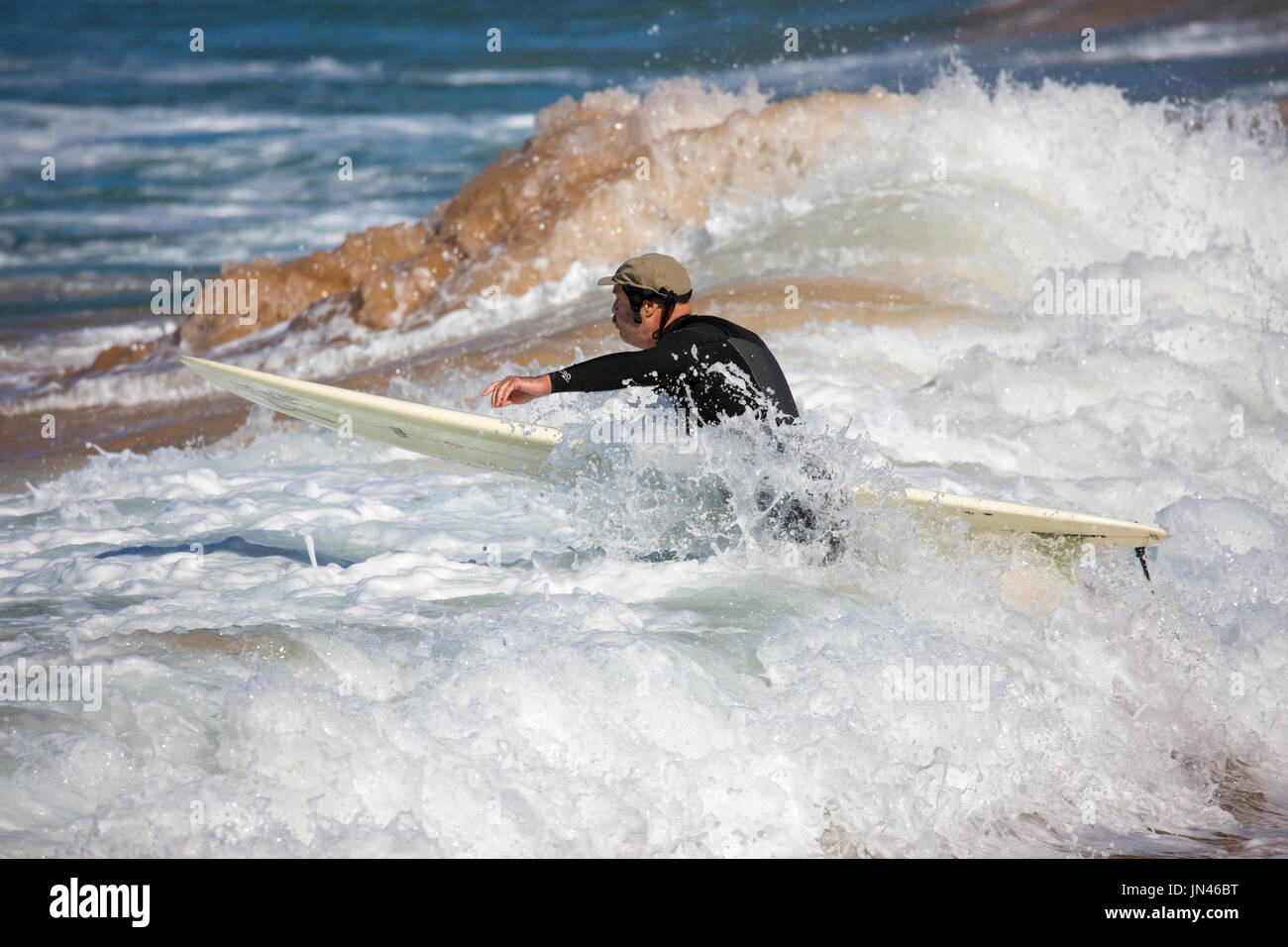 Australischer Mann kämpfen, die Wellen zu Kopf heraus zum Meer mit seinem Surfbrett zum Wellenreiten Zeit, Sydney, Australien Stockfoto