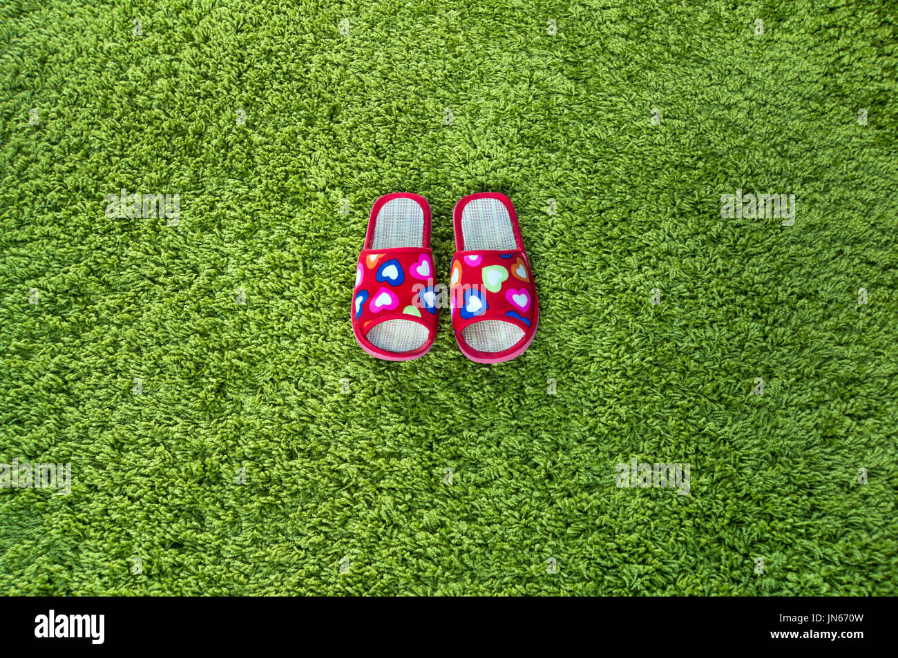 Rosa Pantoffeln auf grüne Fußmatte Hintergrund. paar Damen Hausschuhe. Stockfoto