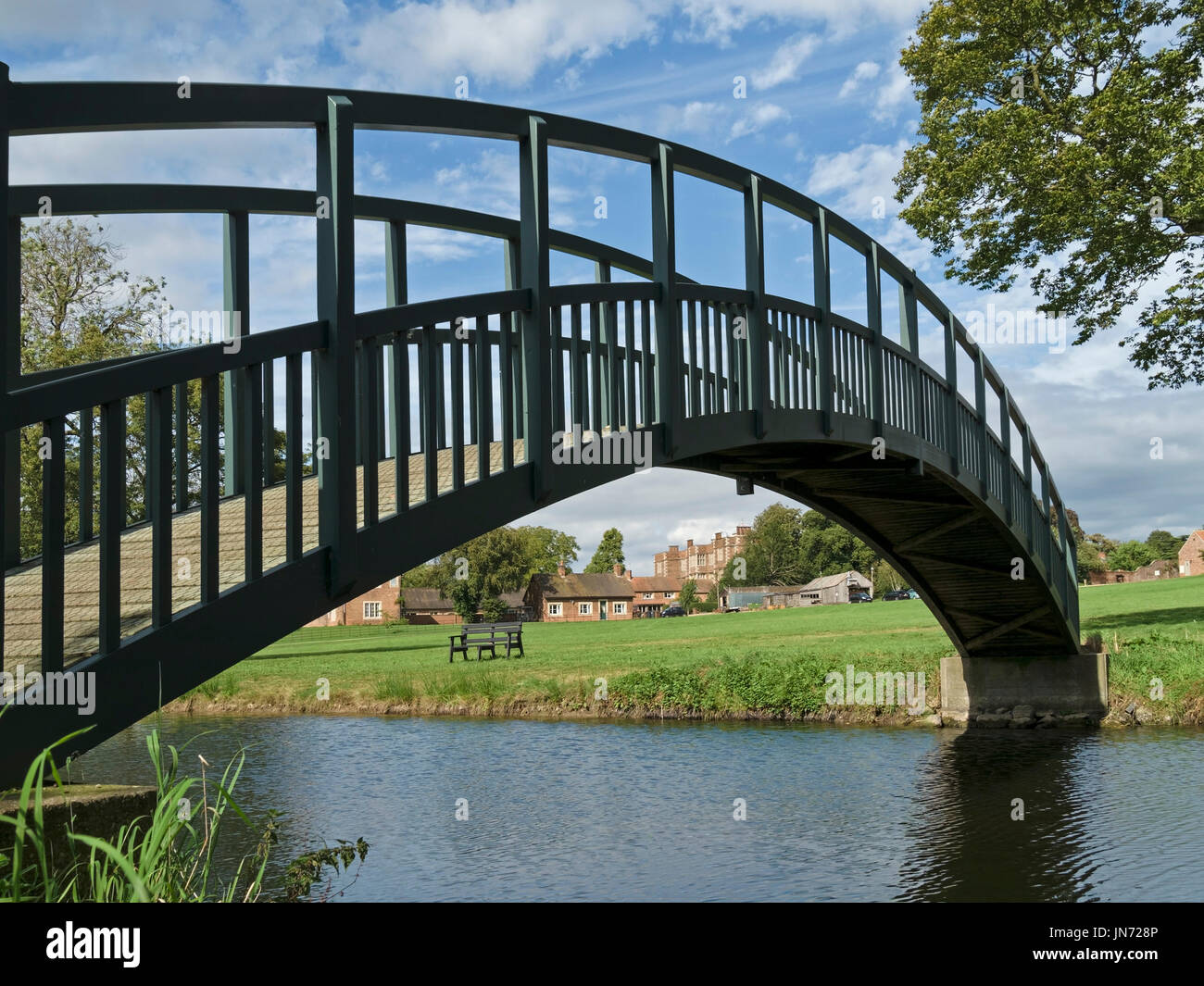 Intelligente neue, einzelne Bogen Fussgänger Holzsteg über den Teich auf dem Gelände des Doddington Hall Estate, Lincolnshire, England, UK Stockfoto