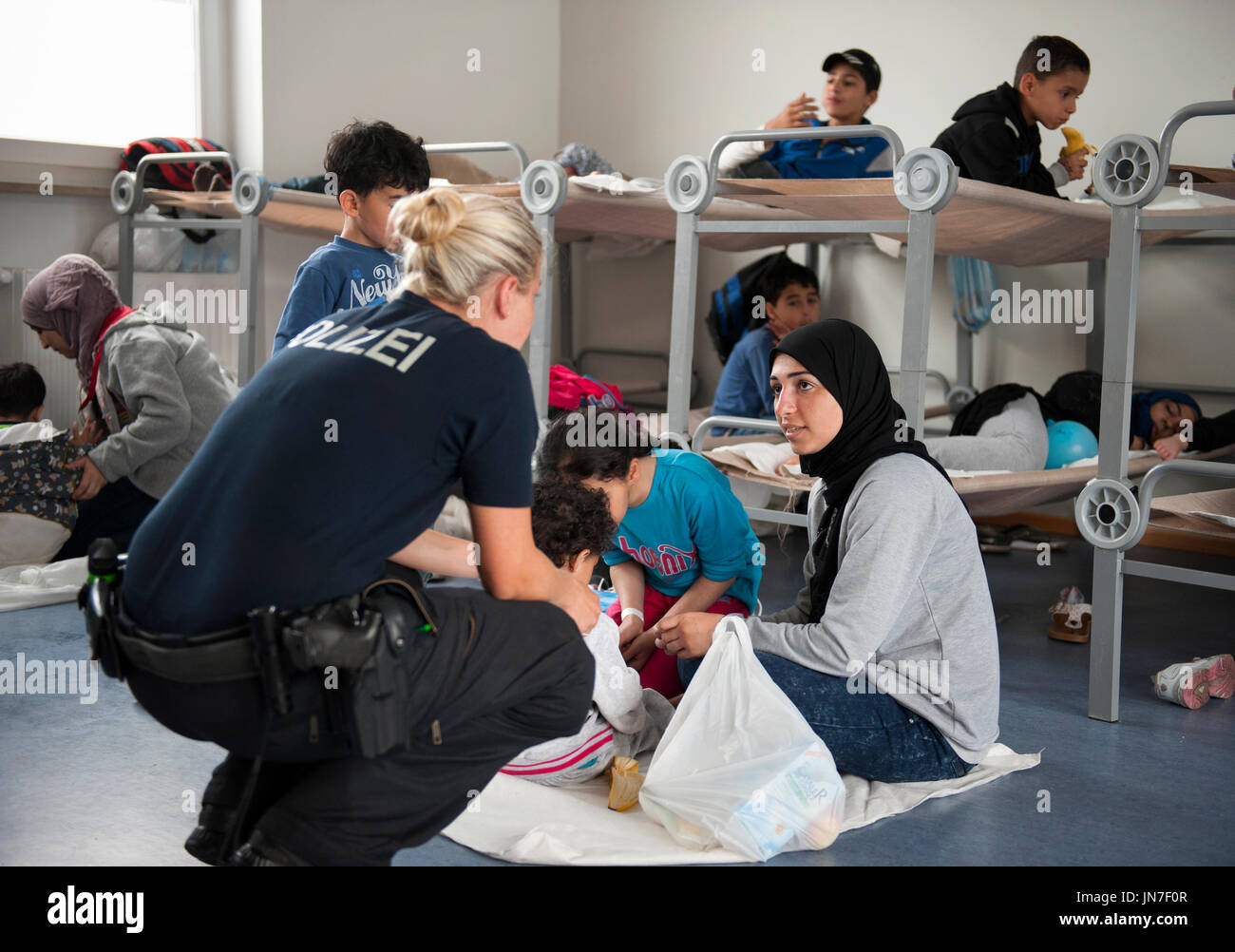 Passau, Deutschland - 2. August 2015: Eine deutsche Polizistin ein junger Flüchtling-Mutter und Kinder werden im Registrierungsbereich "in Passau, Bavar kümmert sich Stockfoto