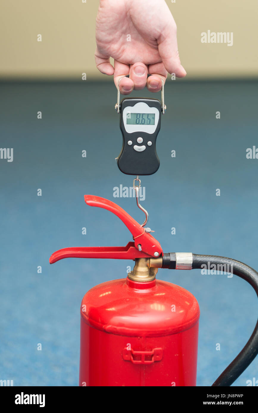 mit einem Gewicht von einen Feuerlöscher, eine Überprüfung der Feuer kämpfende Ausrüstung Stockfoto