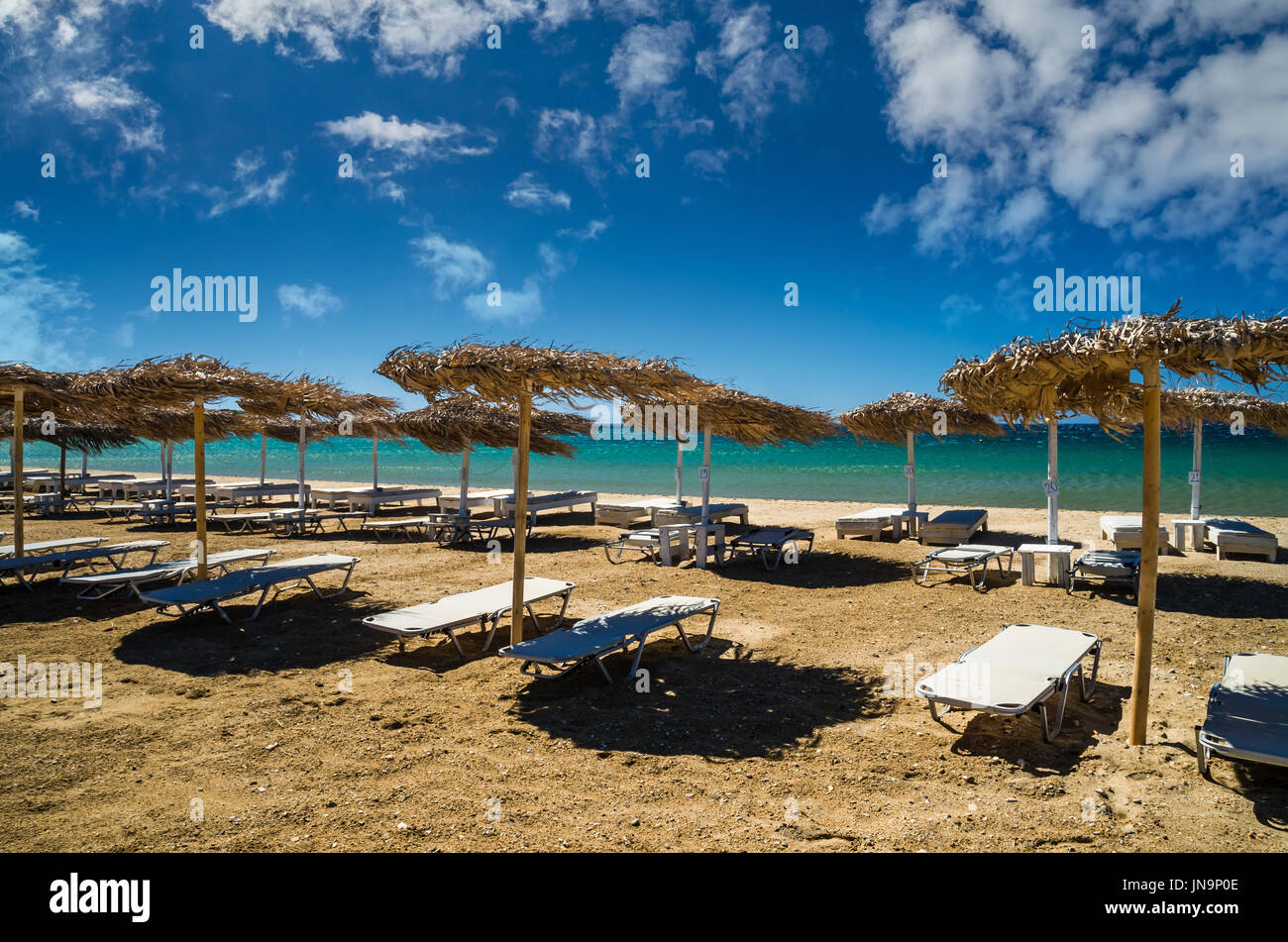 Insel Paros, Kykladen, Griechenland. Stroh Sonnenschirme und Strand liegen am Golden Beach. Stockfoto