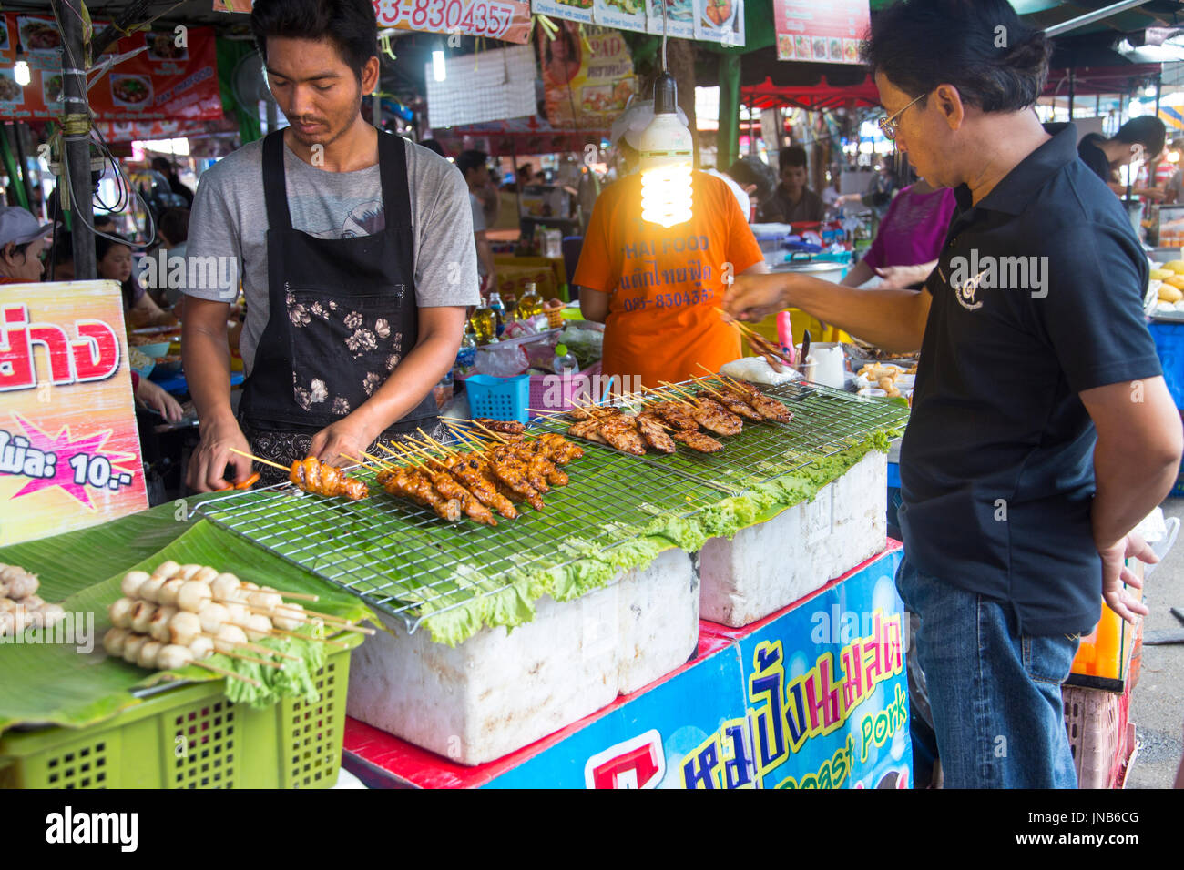 Mann kaufen Fleischspieße an Chatuchak Market, Bangkok, Thailand Stockfoto