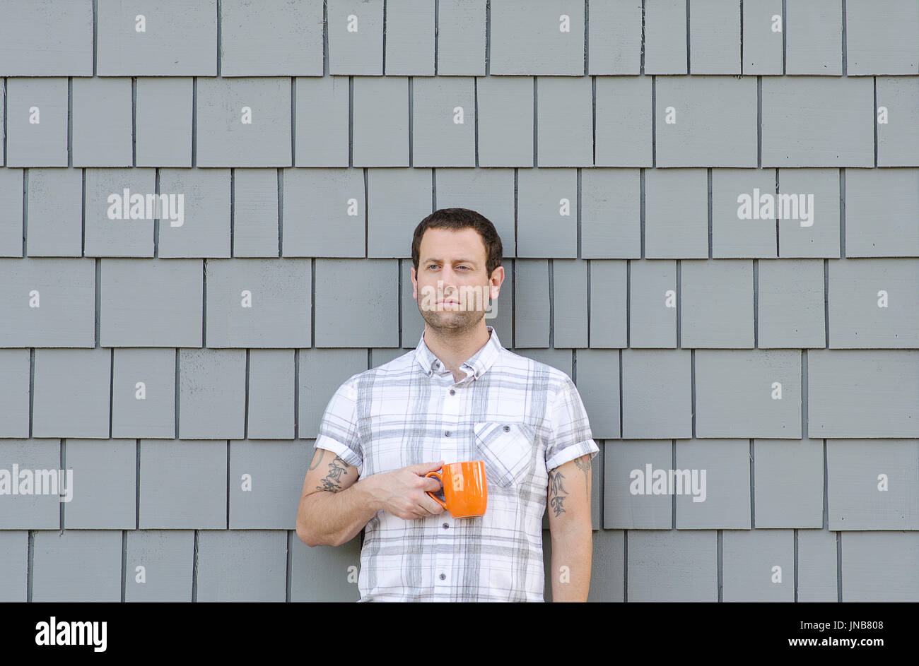 Retro Mann gegen einen grauen monochromen Hintergrund Holding eine Kaffeetasse. Stockfoto