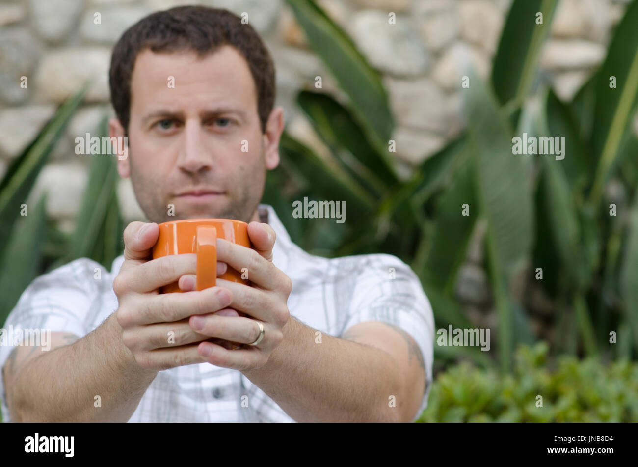 Mann aus dem Fokus Holding eine orange Kaffeebecher vor ihm mit der Becher im Fokus. Stockfoto