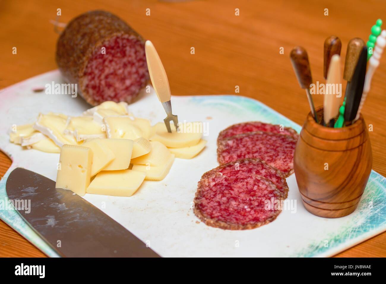 Hausgemachte Partei Vorbereitung. Geschnittene Salami und Käse auf weiße Schneidebrett Stockfoto