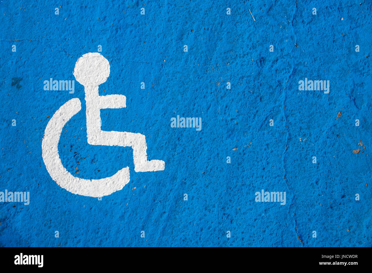 Weiße Behindertenparkplatz-Schild gemalt auf blauem Hintergrund Stockfoto