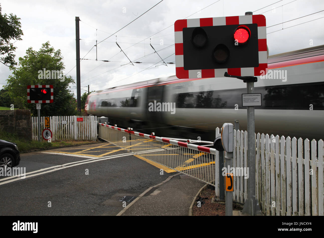 Eine Jungfrau Bahn durchläuft den Bahnübergang in Kirknewton Station in der Nähe von Edinburgh Stockfoto