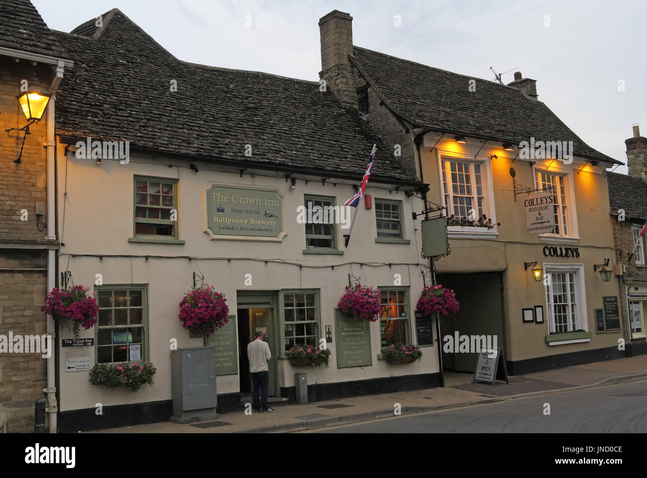 Draußen raucht ein Raucher vor dem Crown Inn in der Abenddämmerung am Lechlade on Thames - Market Square, Lechlade GL7 3AE Stockfoto