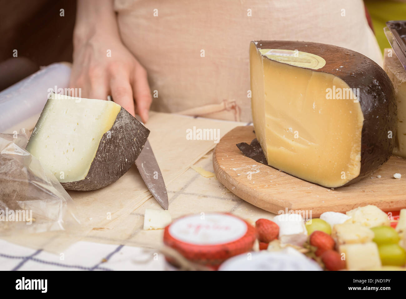 Käse-Köpfe auf den Markt-Theke, Frau Hände des Verkäufers mit Messer abgeschnitten Stockfoto