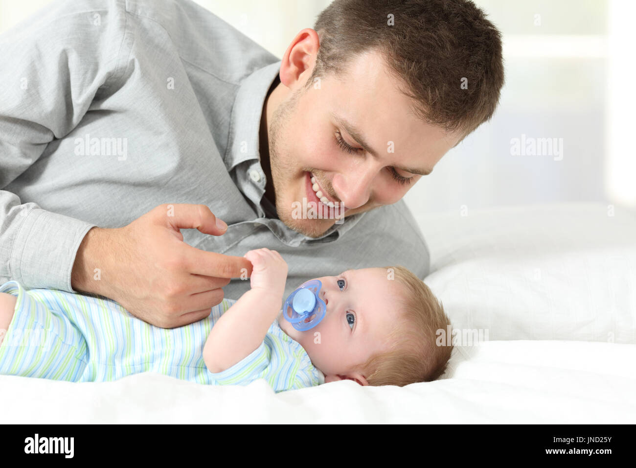 Stolzer Vater mit seinem Sohn auf einem Bett zu Hause spielen Stockfoto