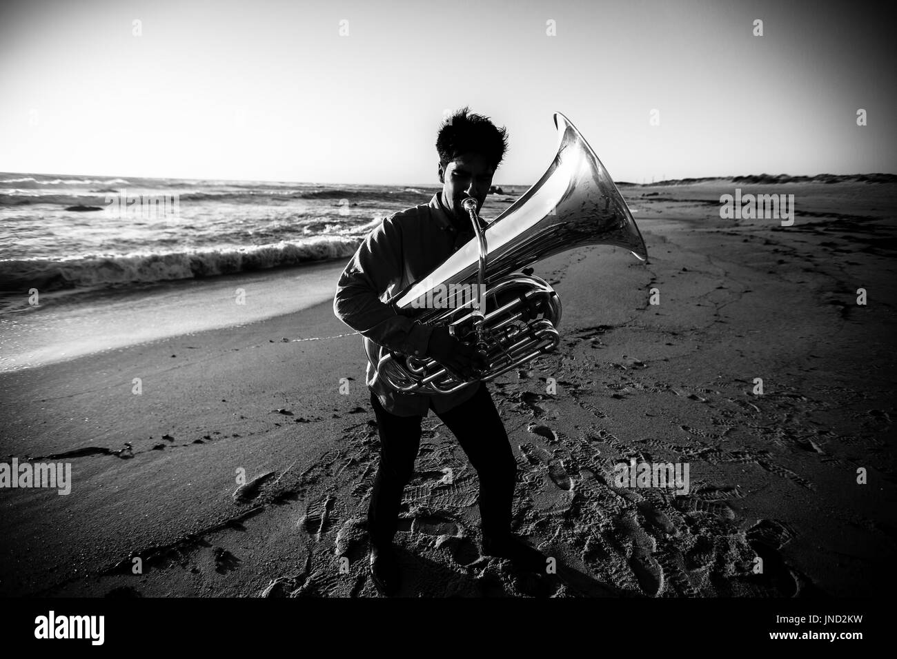 Musiker spielt die Tuba an der Meeresküste. Kontrastreiche schwarz-weiß-Fotografie. Stockfoto