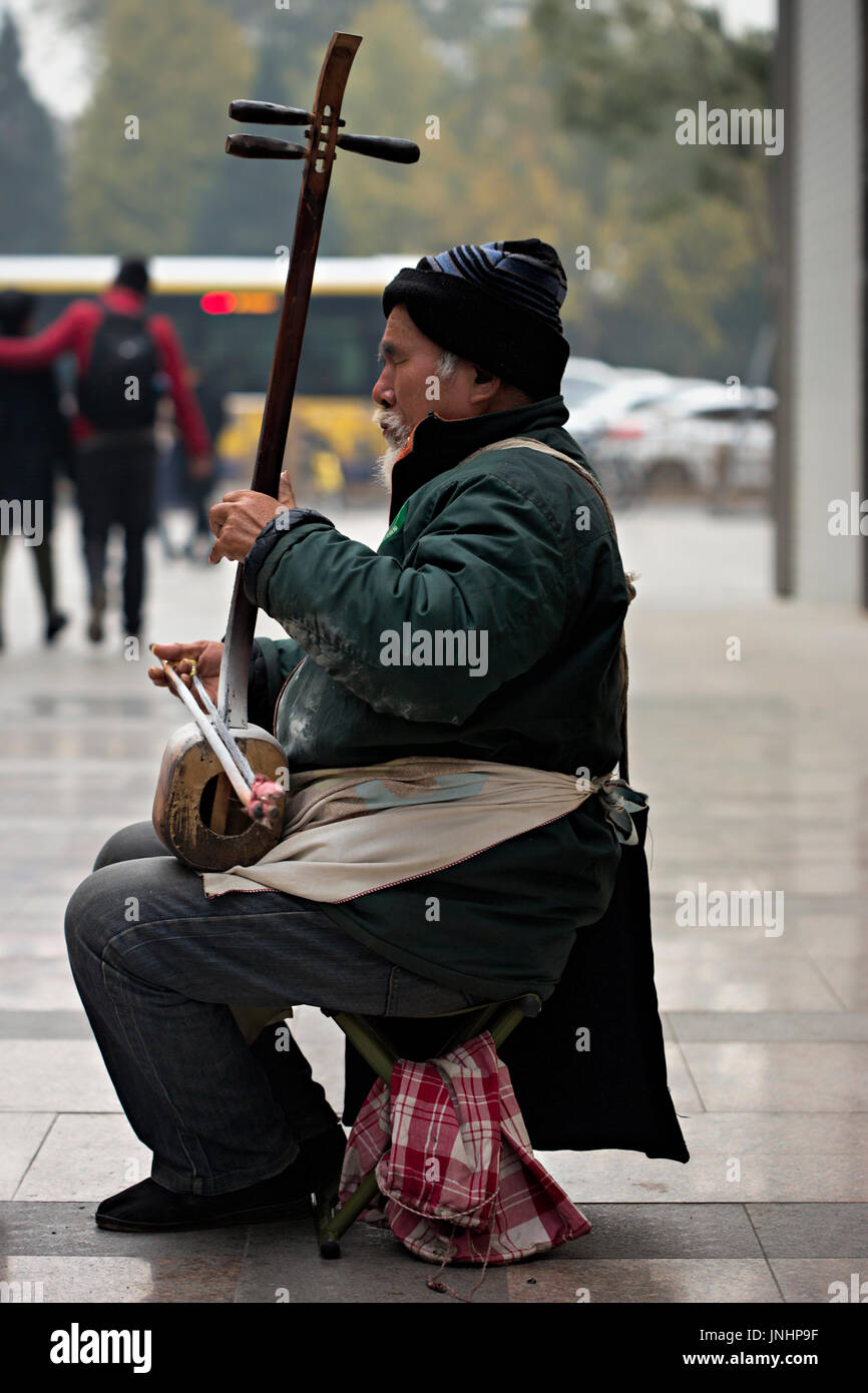 Chinesische alte Musiker spielen auf der Straße auf sanxian Laute - Ein 3-Saiter Fretless gerupft Musikinstrument Stockfoto