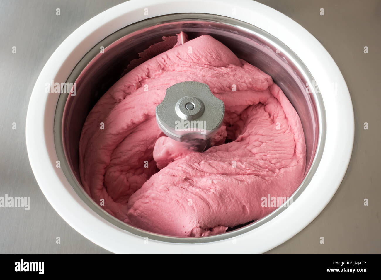 Hausgemachtes Himbeer Eis in eine kleine professionelle Eismaschine Buttern. Stockfoto