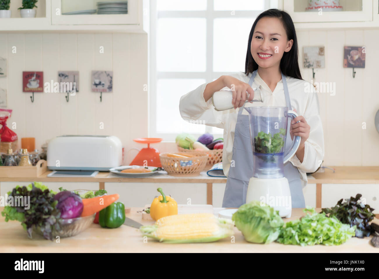 Gemüse-Smoothie. Asiatin macht grüne Smoothies mit Blender zu Hause in der Küche. Gesunden roh essen Lifestyle Konzept Porträt von schöne junge Stockfoto