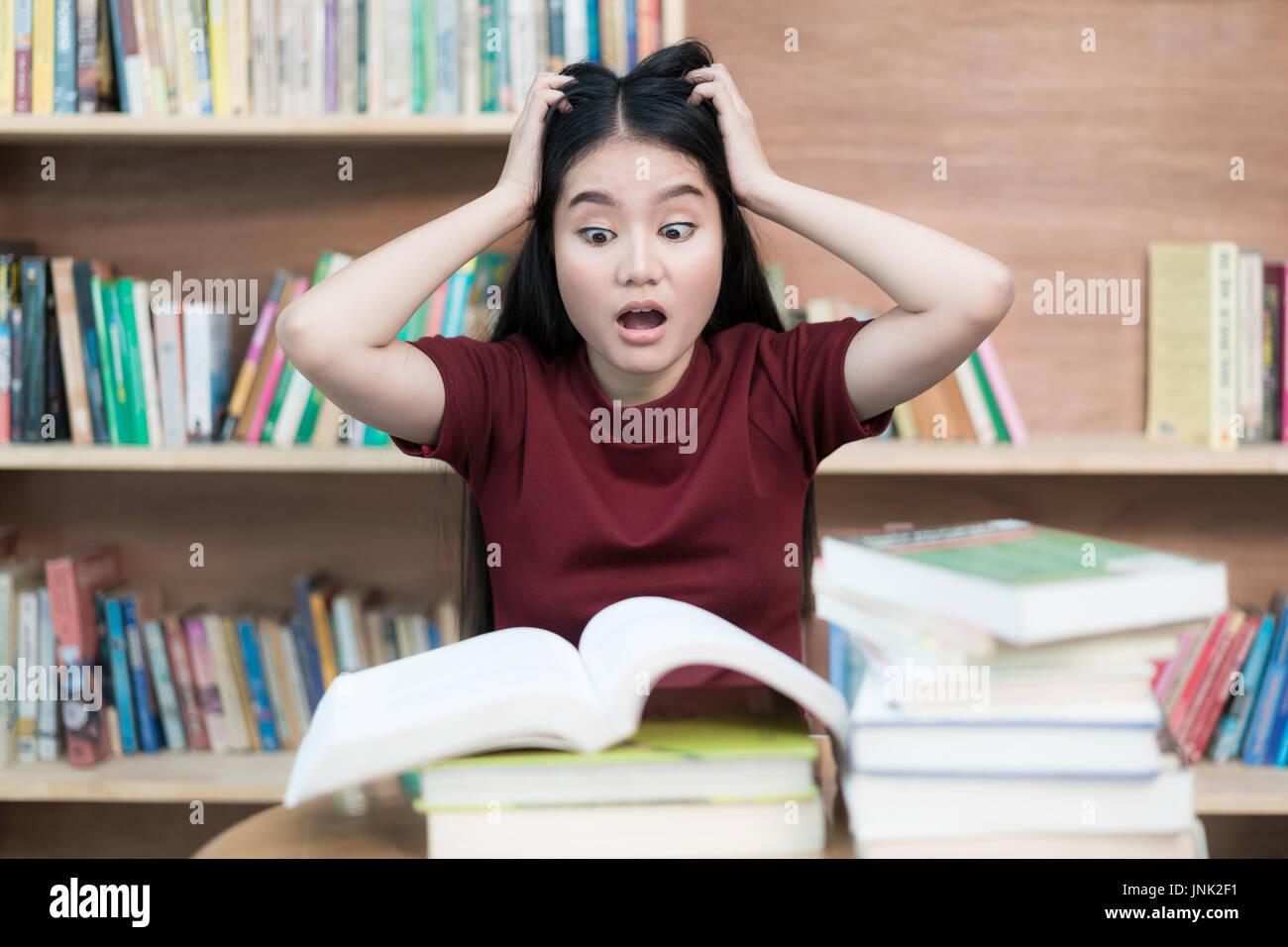 Junge asiatische Studentin unter psychischen Druck Buch Vorbereitung Prüfung in Bibliothek an der Universität. Asiatische Studentin sucht gestresst. Stockfoto