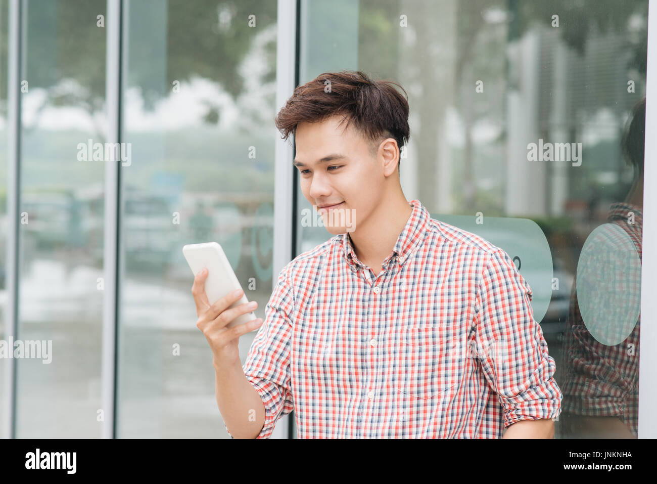 Hübscher junger asiatischer Mann Blick auf Handy Stockfoto