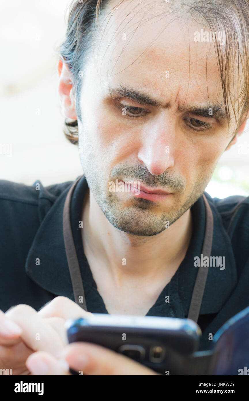 Porträt eines jungen, gut aussehend, kaukasische mit stoppeligen Bart mit mobilen Smartphone Stockfoto