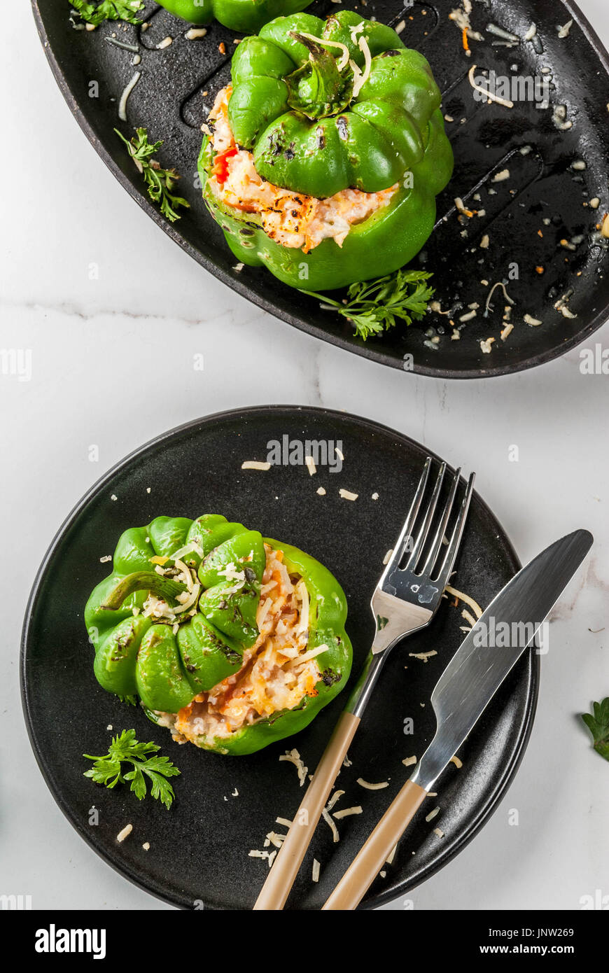 Herbst Rezepte. Hausgemachte gefüllte Paprika mit Hackfleisch, Karotten, Tomaten, Kräuter, Käse. Auf weissem Marmortisch, portioniert in Platte, mit Messer Stockfoto